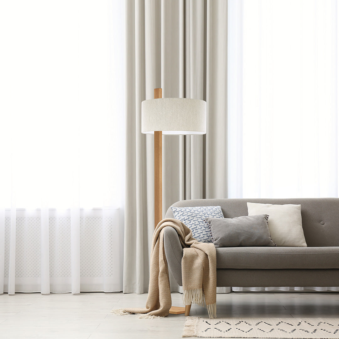Stehleuchte aus Asteiche geölt, Modell Lydia, Schirm in Leinenoptik, Metall Nickel matt gebürstet, Milieubild im Wohnzimmer, Leuchte steht neben Sofa