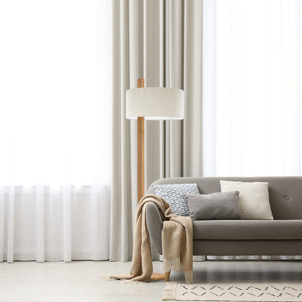 Stehleuchte aus Asteiche geölt, Modell Lydia, Schirm in Leinenoptik, Metall Nickel matt gebürstet, Milieubild im Wohnzimmer, Leuchte steht neben Sofa