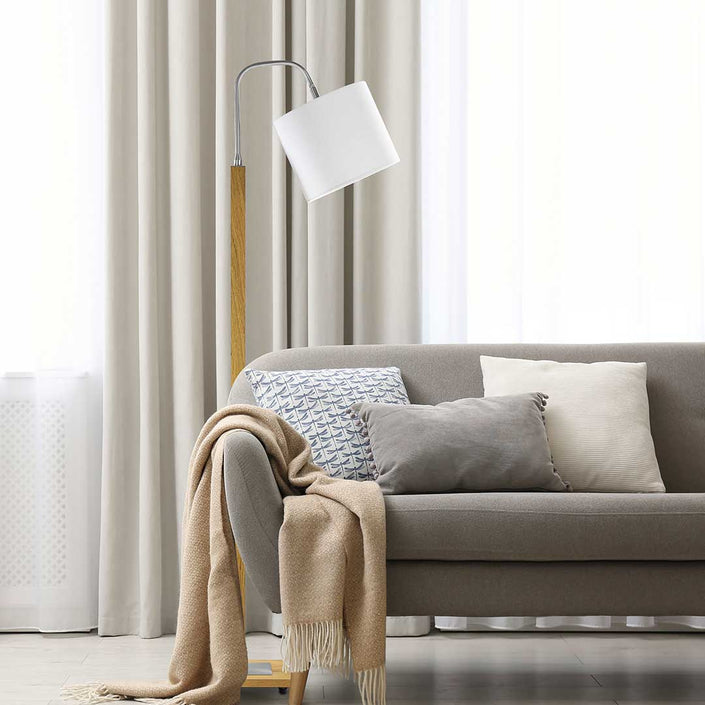 Steh-/Leseleuchte aus Asteiche geölt, Modell Rika, mit weißem Leuchtenschirm, Metall Nickel gebürstet, Seitenansicht, Milieubild im Wohnzimmer, Leuchte steht hinter Sofa