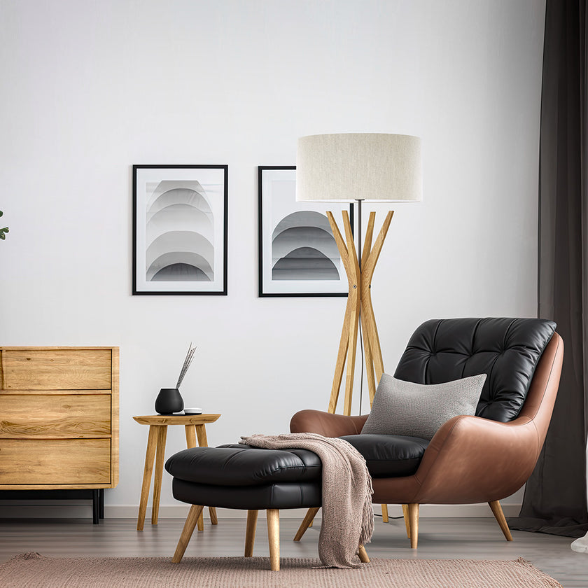 Stehleuchte aus Asteiche geölt, Modell Elody, weißer Schirm, vier sich oben treffende Beine, Stromkabel mittig zwischen Beinen her, Metall schwarz gepulvert, Milieubild im Wohnzimmer, Leuchte steht neben Sessel