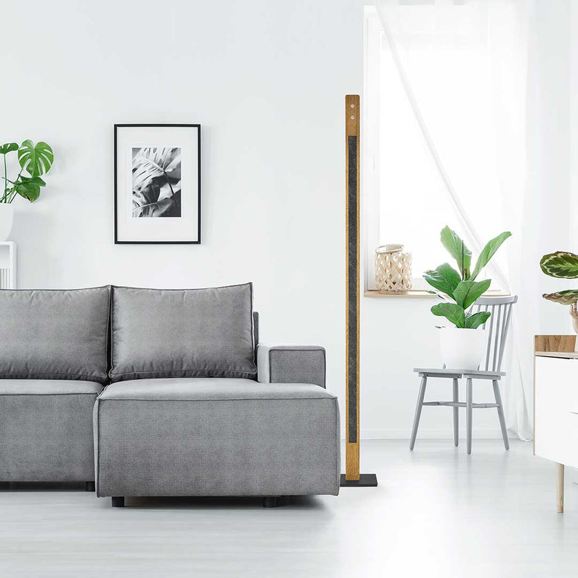 Stehleuchte aus Asteiche geölt und Granitoptikapplikation, Modell Karl G, schwarze Details, Dimm-to-warm-Funktion, Milieubild im Wohnzimmer, Leuchte steht neben Sofa