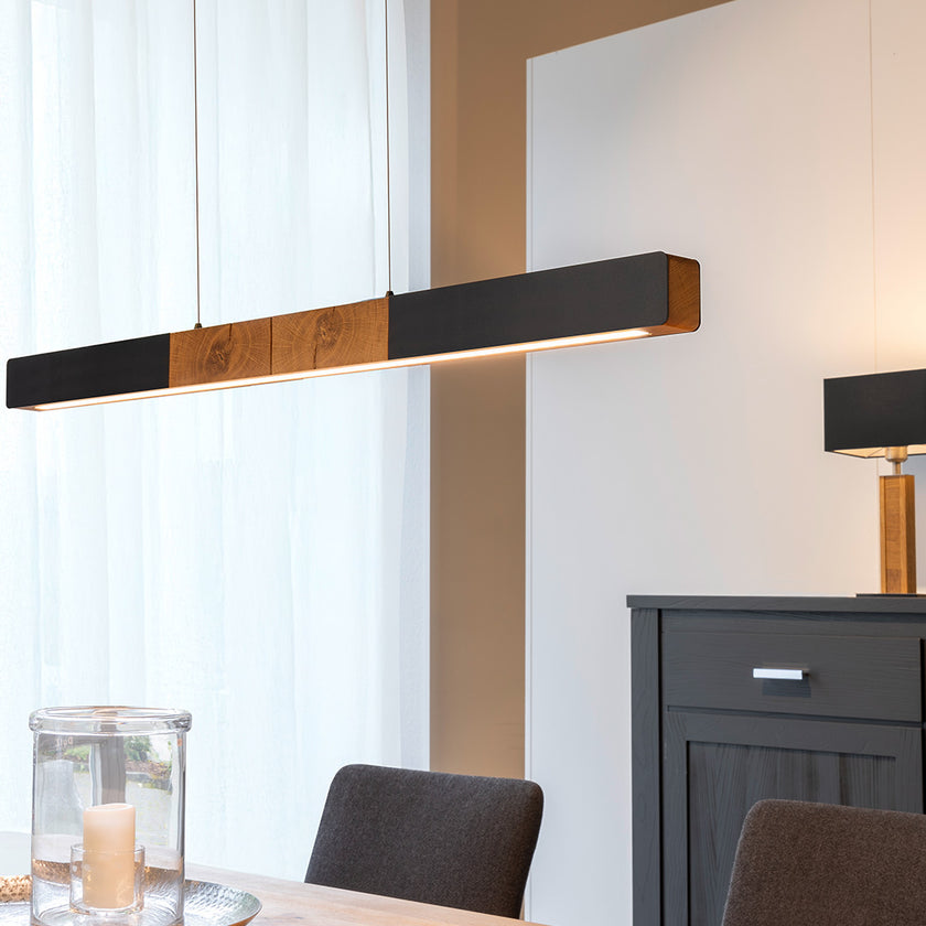 Balkenleuchte aus Asteiche geölt, Modell Lana del nero, 1300mm, Kopfholz, schwarze Applikationen, Dimm to warm per Tastdimmung, Milieubild, Leuchte hängt über Esstisch