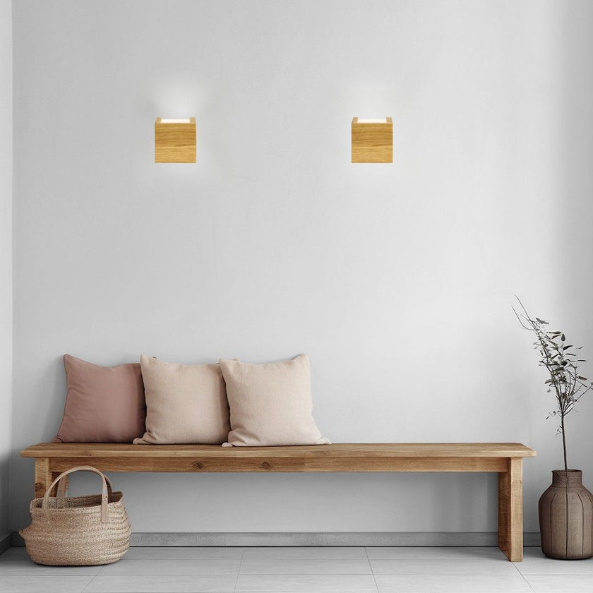 Wandleuchte aus Asteiche geölt, Modell Amon, eckige Form, mit ober und Unterlicht, im Flur fotografiert über einer Bank