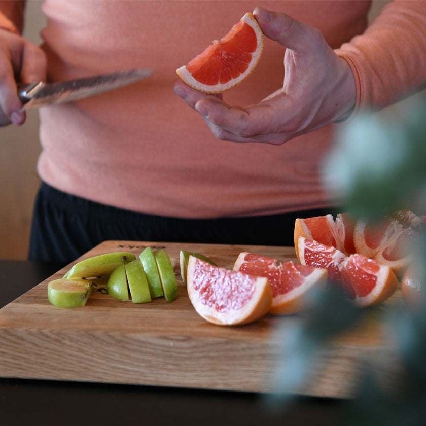 Hackbrett aus Eichenholz Natur, Größe M, COOKX Logo unten rechts eingraviert, Milieubild in Küche, Früchte auf Brett geschnitten 