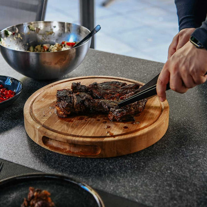 Hackbrett aus Holz Natur, Rund Größe S, 475cm Durchmesser, mit Griffeinkerbung, Milieubild im Garten, Steak liegt auf Brett