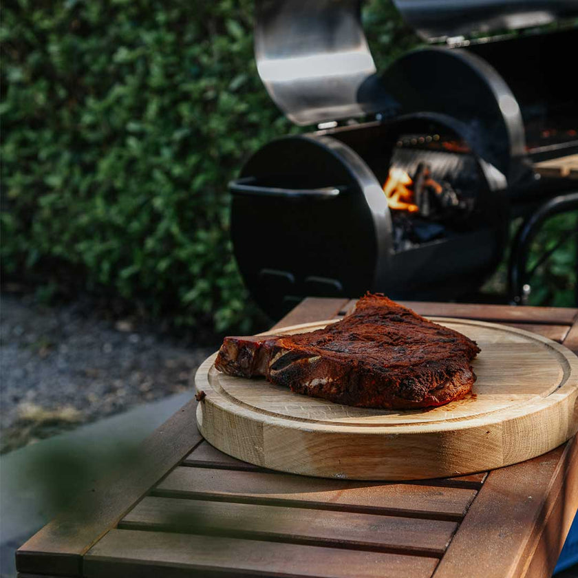 Hackbrett aus Holz Natur, Rund Größe S, 475cm Durchmesser, mit Griffeinkerbung, Milieubild im Garten, Steak liegt auf Brett