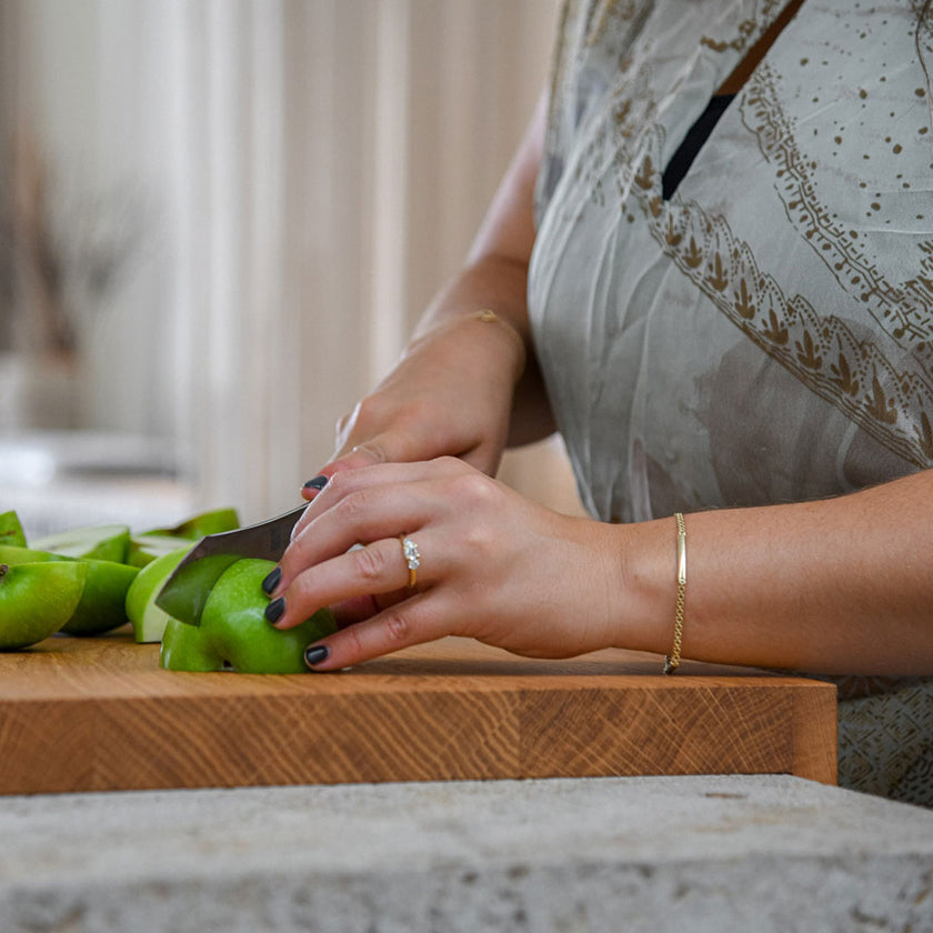 Hackbrett aus Eichenholz Natur, Antirutschkante, COOKX Logo unten rechts eingraviert, 50 x 34 x 3,5 cm, Milieubild in Küche, Frau schneidet grüne Äpfel auf Brett