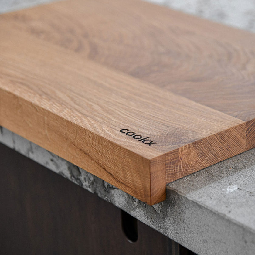 Hackbrett aus Eichenholz Natur, Antirutschkante, COOKX Logo unten rechts eingraviert, 50 x 34 x 3,5 cm, Milieubild in Küche, Seitenansicht schräg