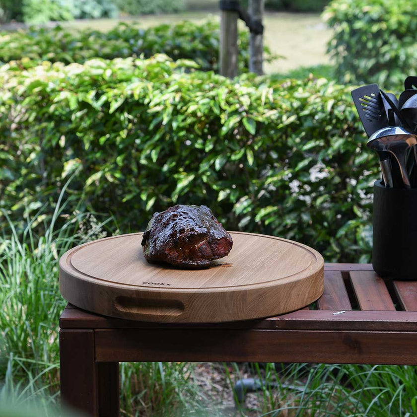 Hackbrett aus Holz Natur, Rund Größe M, mit Griffeinkerbung, Milieubild im Garten, Steak liegt auf Brett