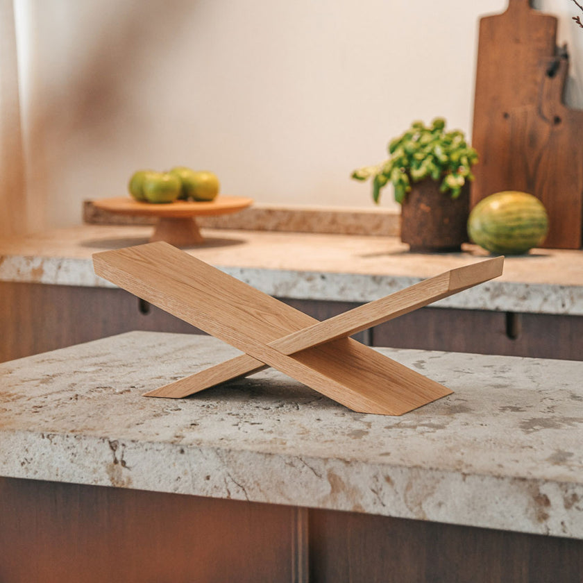 Buchständer aus Eichenholz, x-From, aus zwei gekreuzten Holzelementen, Milieubild frontal auf Arbeitsfläche in der Küche