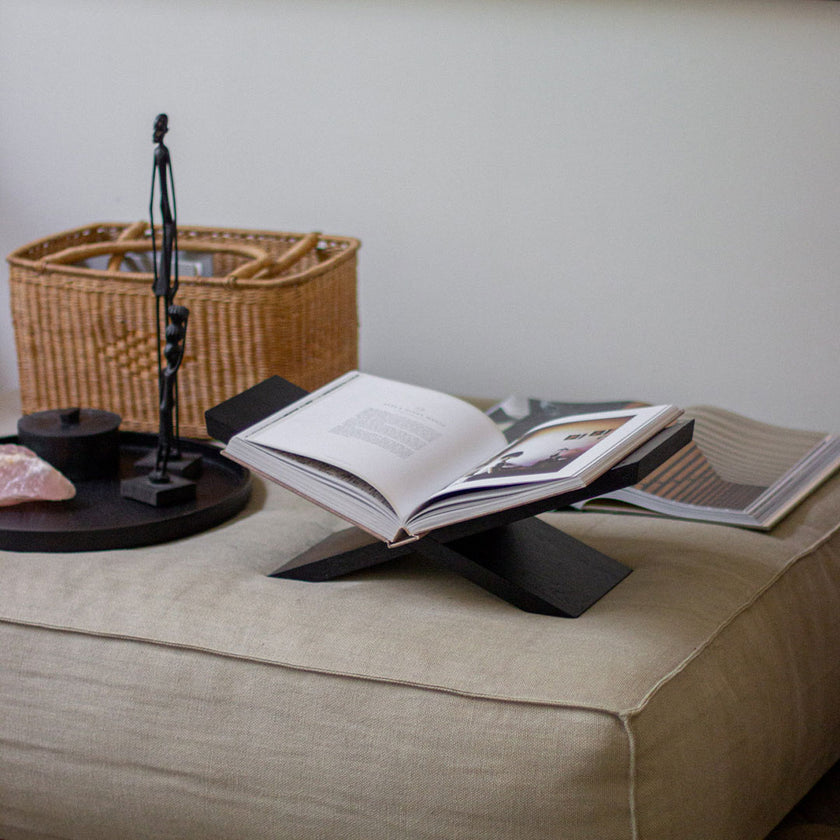 Buchständer aus Eichenholz schwarz, x-From, aus zwei gekreuzten Holzelementen, Milieubild frontal auf Hocker mit Buch