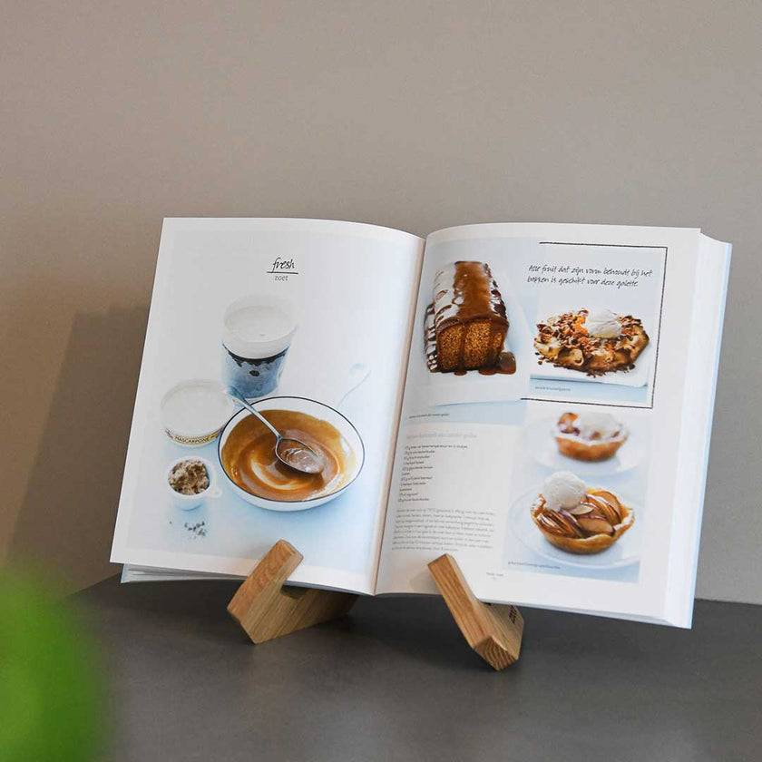 Buchständer in X-Form aus naturfarbener Eiche, minimalistisches Design mit geschwungenen Haken-Enden, Milieubild mit Buch drauf