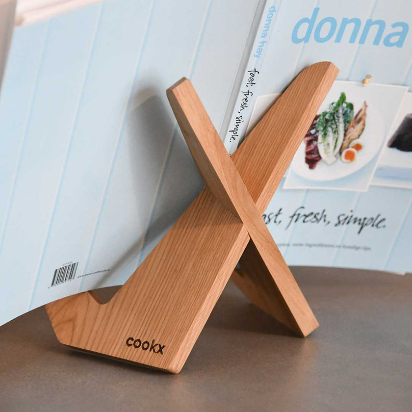 Buchständer in X-Form aus naturfarbener Eiche, minimalistisches Design mit geschwungenen Haken-Enden, Milieubild mit Buch drauf