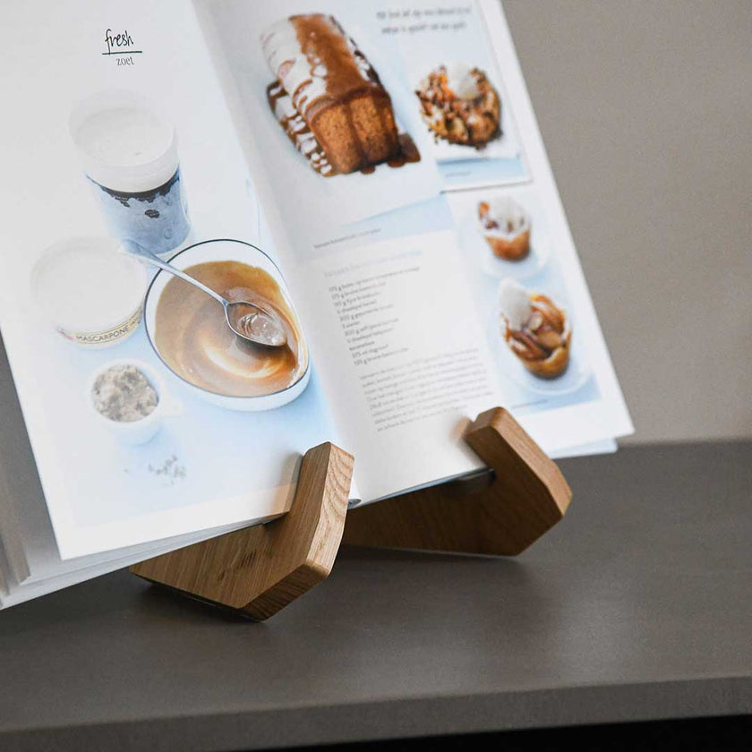 Buchständer in X-Form aus naturfarbener Eiche, minimalistisches Design mit geschwungenen Haken-Enden, Milieubild mit Buch drauf