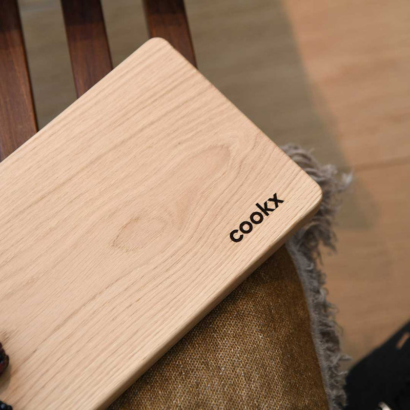 Servierbrett oder Schneidebrett aus Eichenholz Natur, Milieubild im Wohnzimmer auf Bank, Brett liegt auf Decke, Ansicht untere Hälfte ohne Griff