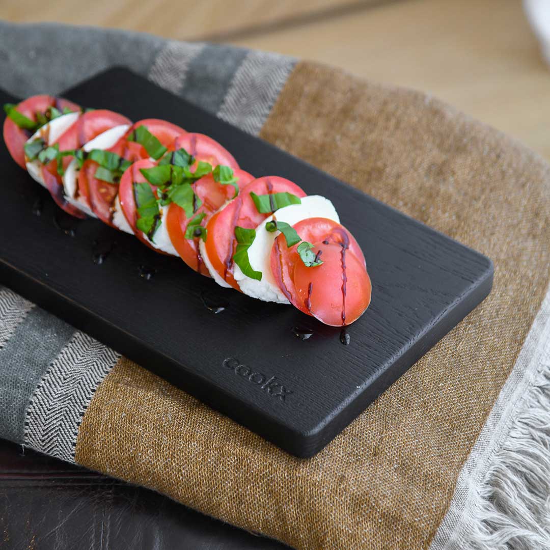 Servierbrett oder Schneidebrett aus Eichenholz schwarz, 400mmx180mmx25mm, Milieubild in Küche, Brett mit Tomate Mozzarella drauf