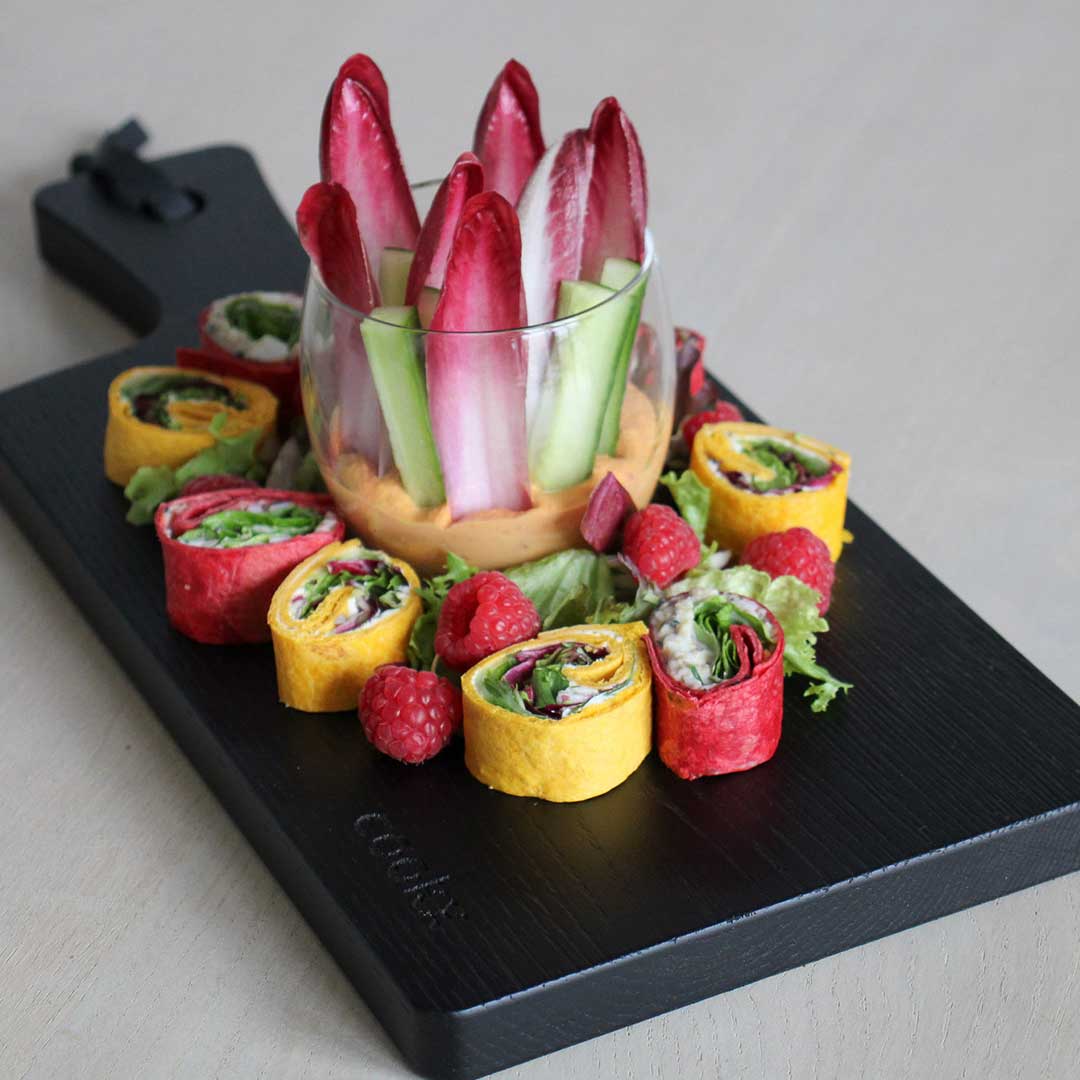 Servierbrett oder Schneidebrett aus Eichenholz schwarz mit Griff und schwarzem Lederband zum aufhängen, 400mmx180mmx25mm, Milieubild in Küche, Brett mit Essen drauf, Ansicht von Oben