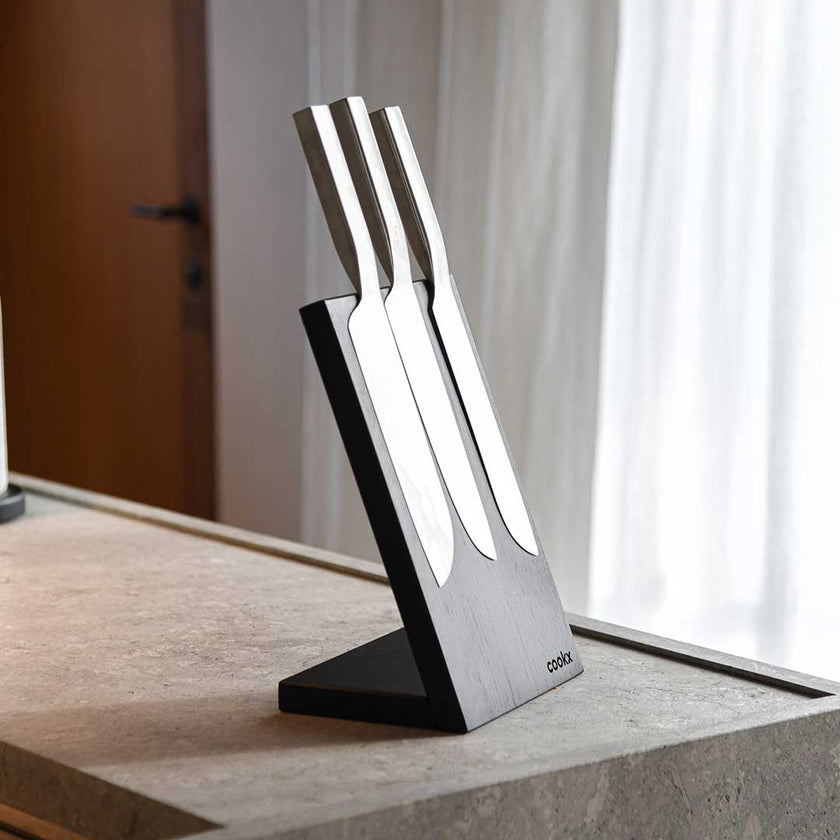 Messerblock aus Eichenholz schwarz, magnetisch, Messerblock schräg nach hinten geneigt, Milieubild in Küche, drei Messer am Messerblock 