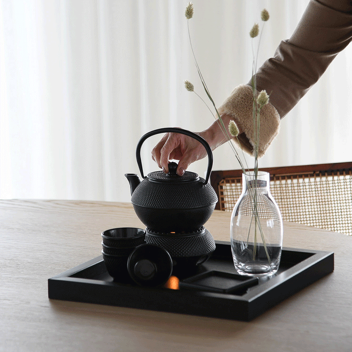 Serviertablett aus Eichenholz schwarz, 40cm x 40cm, Ränder etwas höher, Milieubild im Esszimmer, Tablett steht auf Tisch, Teekanne und Deko stehen auf Serviertablett, Ansicht seitlich   