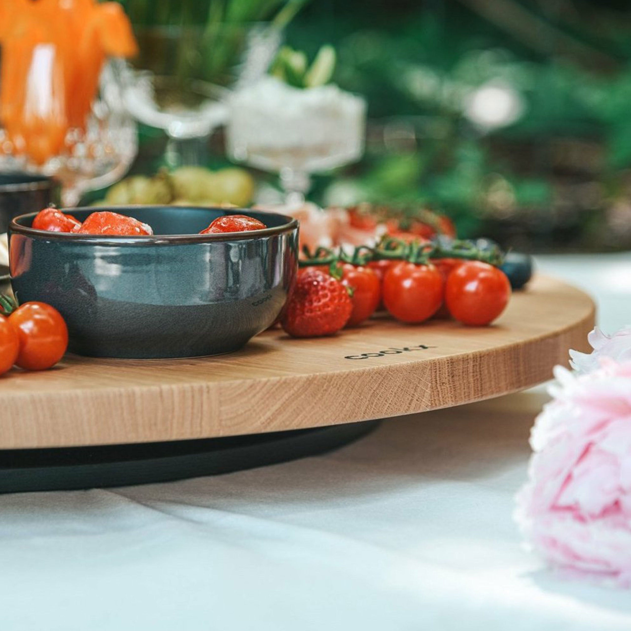 Drehteller aus Eichenholz Natur, Größe M, ca. 50 cm Durchmesser, Milieubild im Garten, Teller mit Tomaten und Früchten auf Gartentisch, Seitenansicht