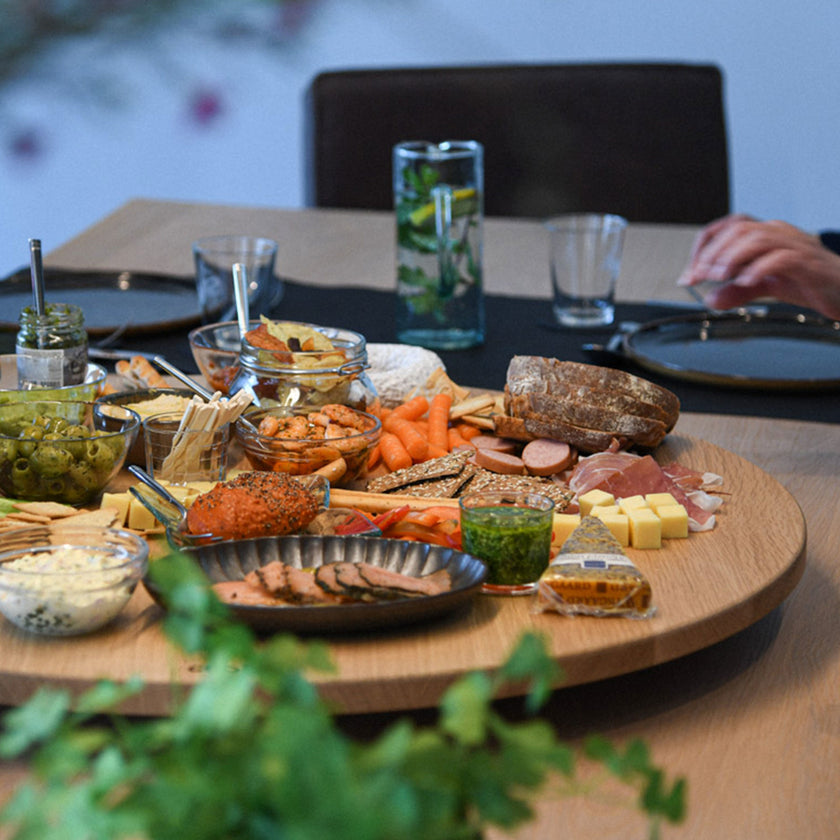 Drehteller aus Eichenholz Natur, Größe XL, 75cm Durchmesser, rund, COOKX Logo eingraviert, Milieubild im Esszimmer, Teller mit verschiedenem Essen drauf steht auf Tisch