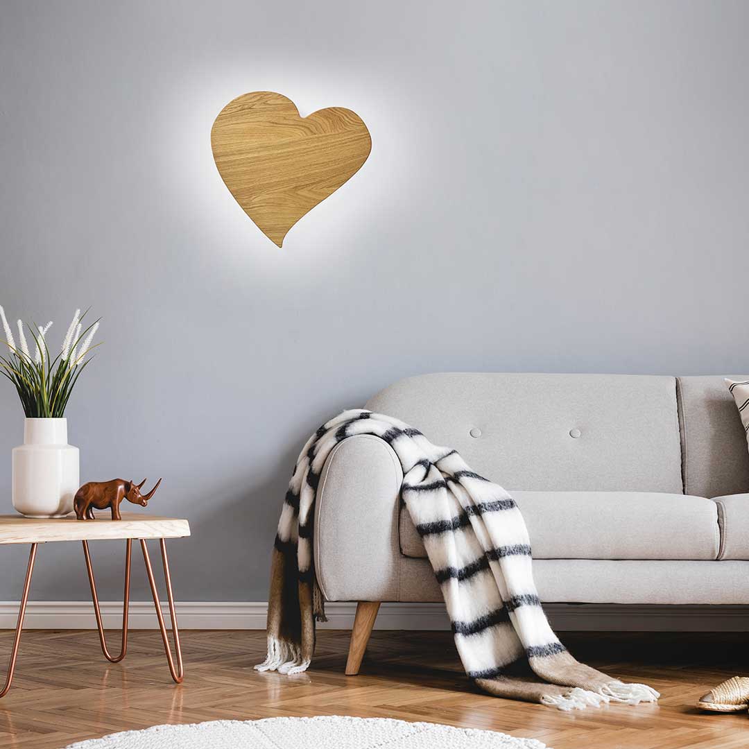 Wandleuchte aus Asteiche geölt, Modell HerzBlut Herz midi, LED, 445mm breit, 430mm hoch, Milieubild im Wohnzimmer, Leuchte hängt an Wand über Sofa