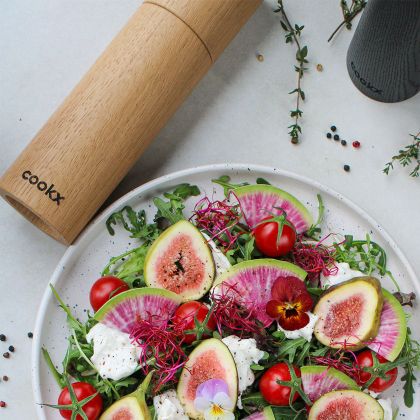 Salz-/Pfeffermühle aus Holz Natur, 23cm hoch, Milieubild in Küche, Salz-/Pfeffermühle liegt neben Teller mit Salat, Ansicht von oben