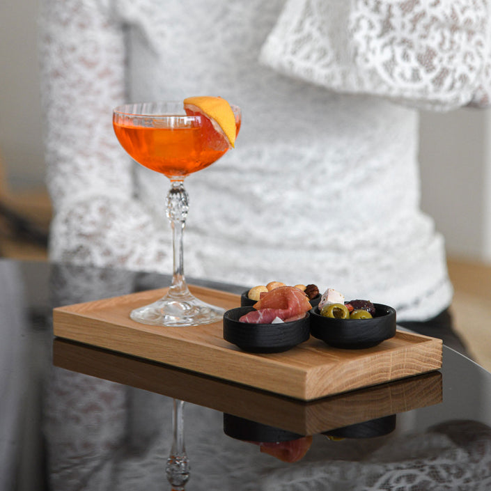 Kerzentablett aus Eichenholz Natur,  28 x 14 x 2,3 cm, Milieubild in Küche, auf Tablett stehen 3 kleine schwarze Schüsseln mit Essen und ein Cocktailglas mit Aperol