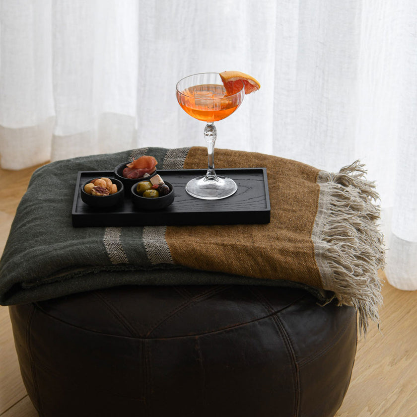 Kerzentablett aus Eichenholz schwarz,  28 x 14 x 2,3 cm, Milieubild auf Hocker, auf Tablett stehen 3 kleine schwarze Schüsseln mit Essen und ein Cocktailglas mit Aperol