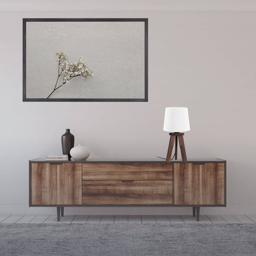 Dreibein Tischleuchte aus Nussbaum, Modell Tre, mit weißem Lampenschirm, Kabel verläuft mittig zwischen den Beinen, Milieubild im Wohnzimmer auf einem Sideboard